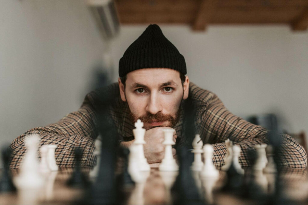 Foto van een man met een schaakbord. Hij denkt na over zijn volgende zet.