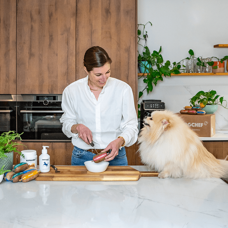 Foto van een vrouw die haar hond Dog Chef geeft op het keukeneiland.